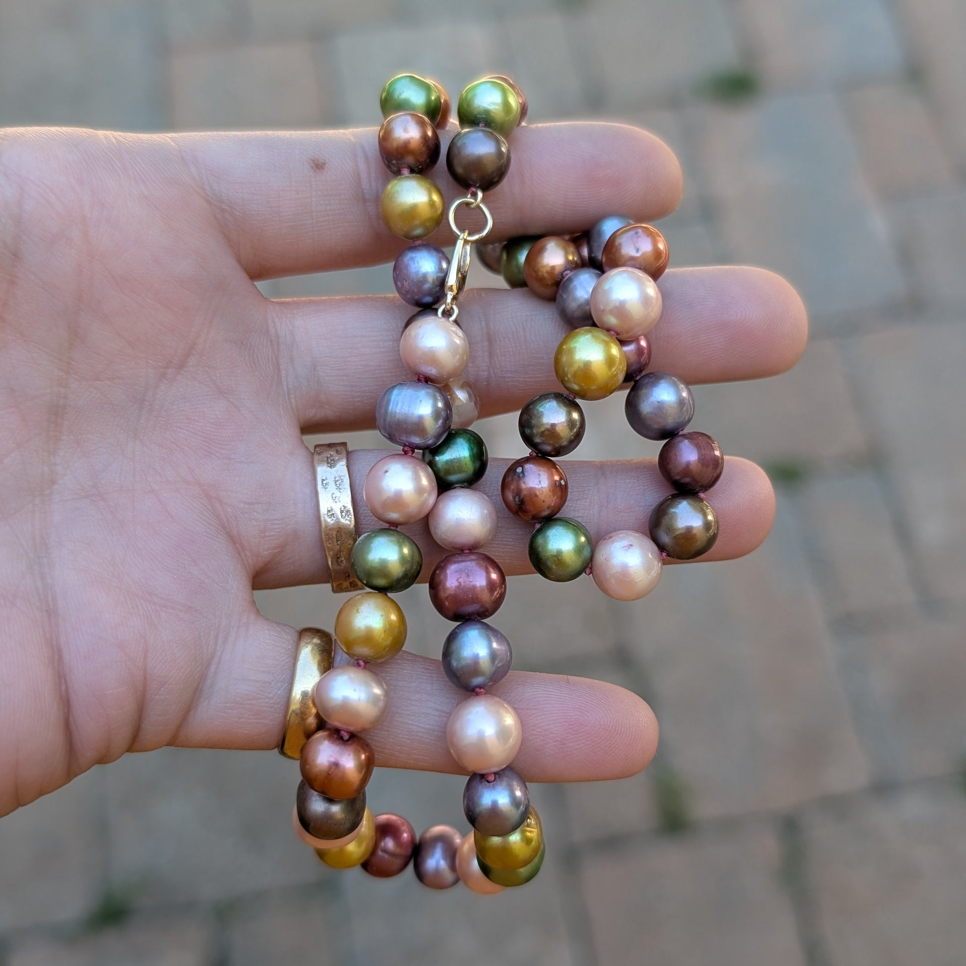 Hand holding a set of colorful pearl on a blurred pavement background