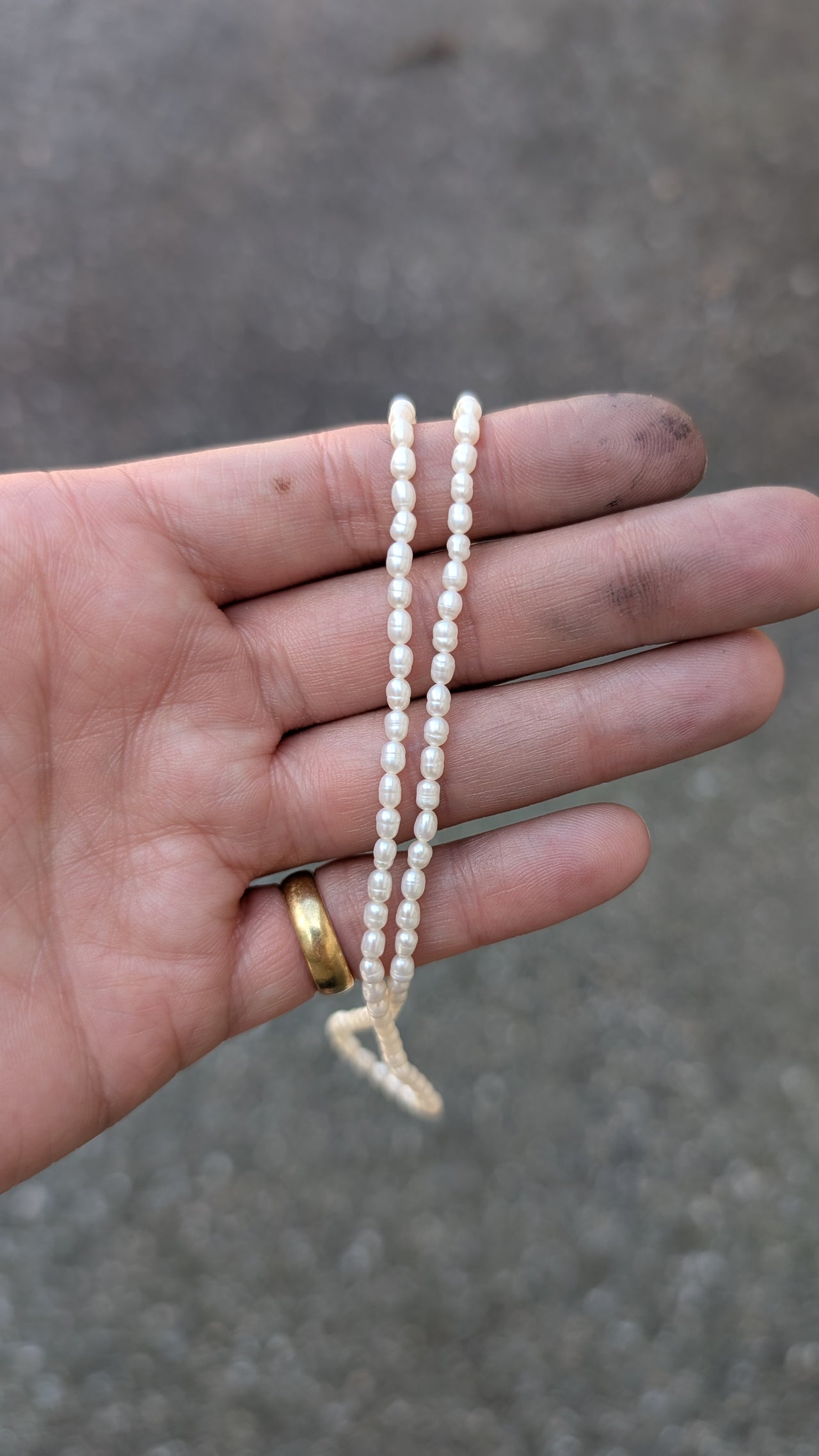 Hand holding a small string of pearls against a blurred background
