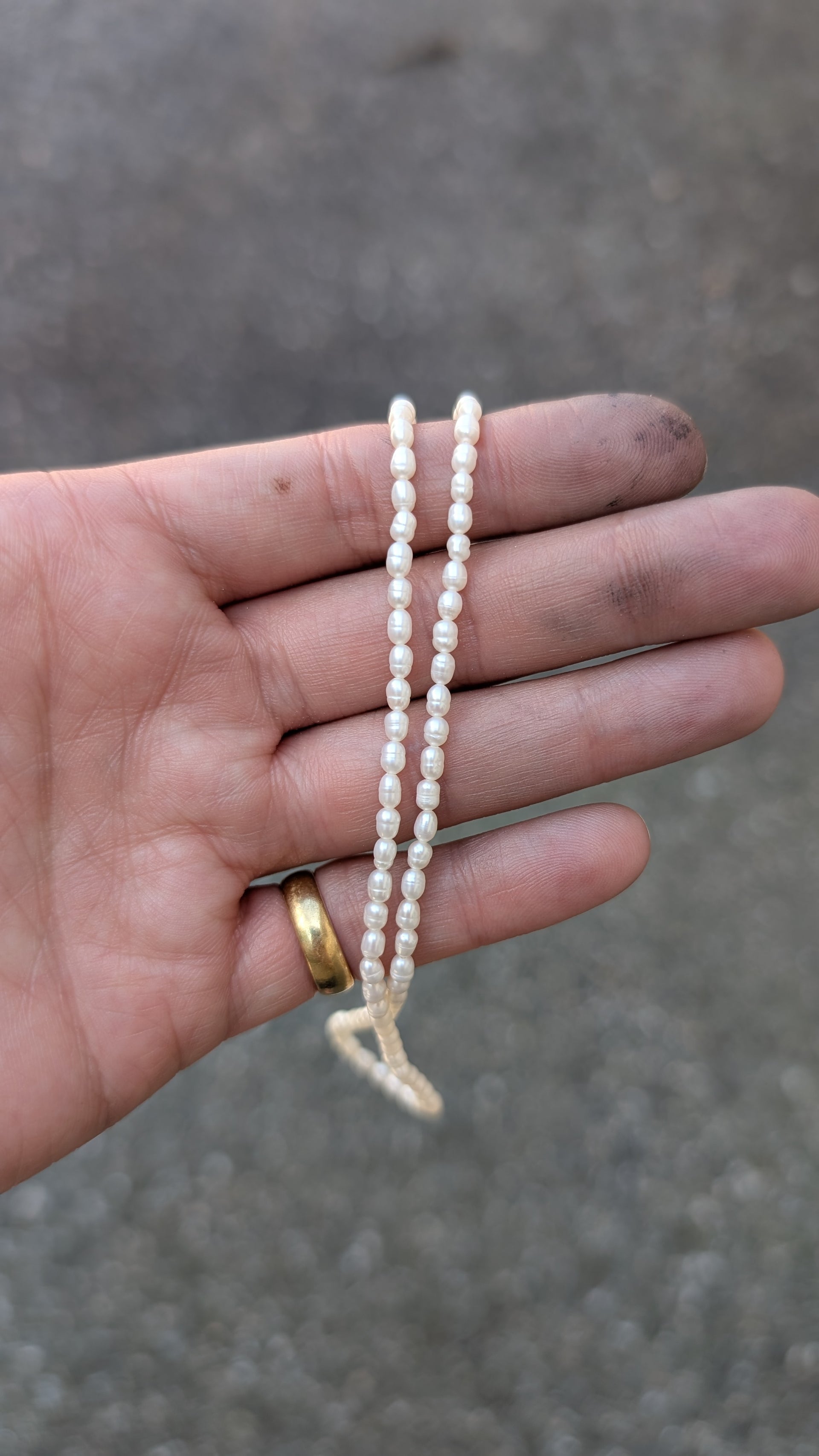 Hand holding a small string of pearls against a blurred background